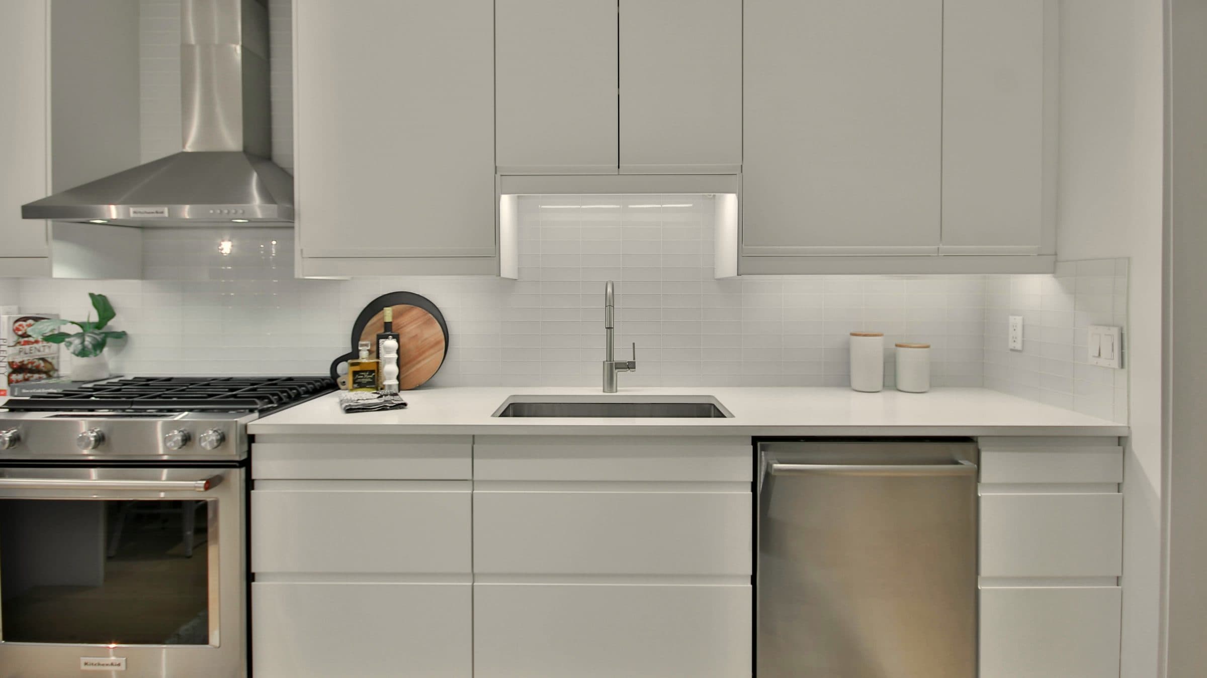 A bright kitchen with a range, a sink and a stainless dishwasher